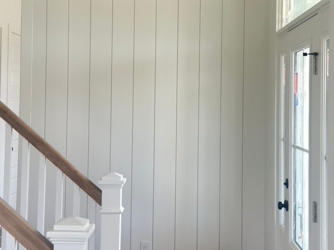 Entry with vertical shiplap and stained stair rail