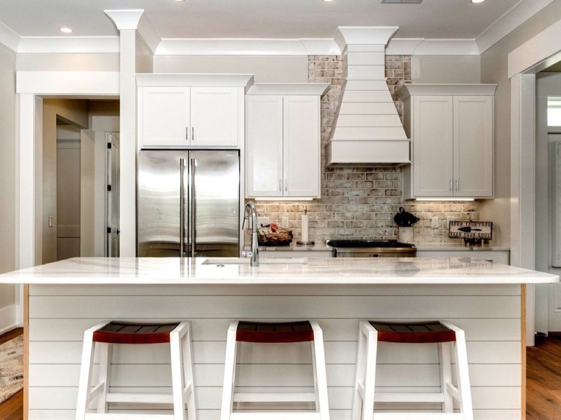 Kitchen with custom hood, brick backsplash, and marble island