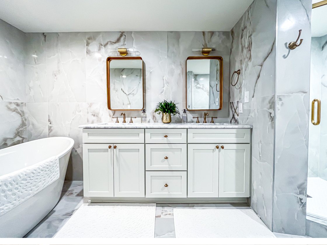 Primary bath with marble tile, freestanding tub, and brass fixtures