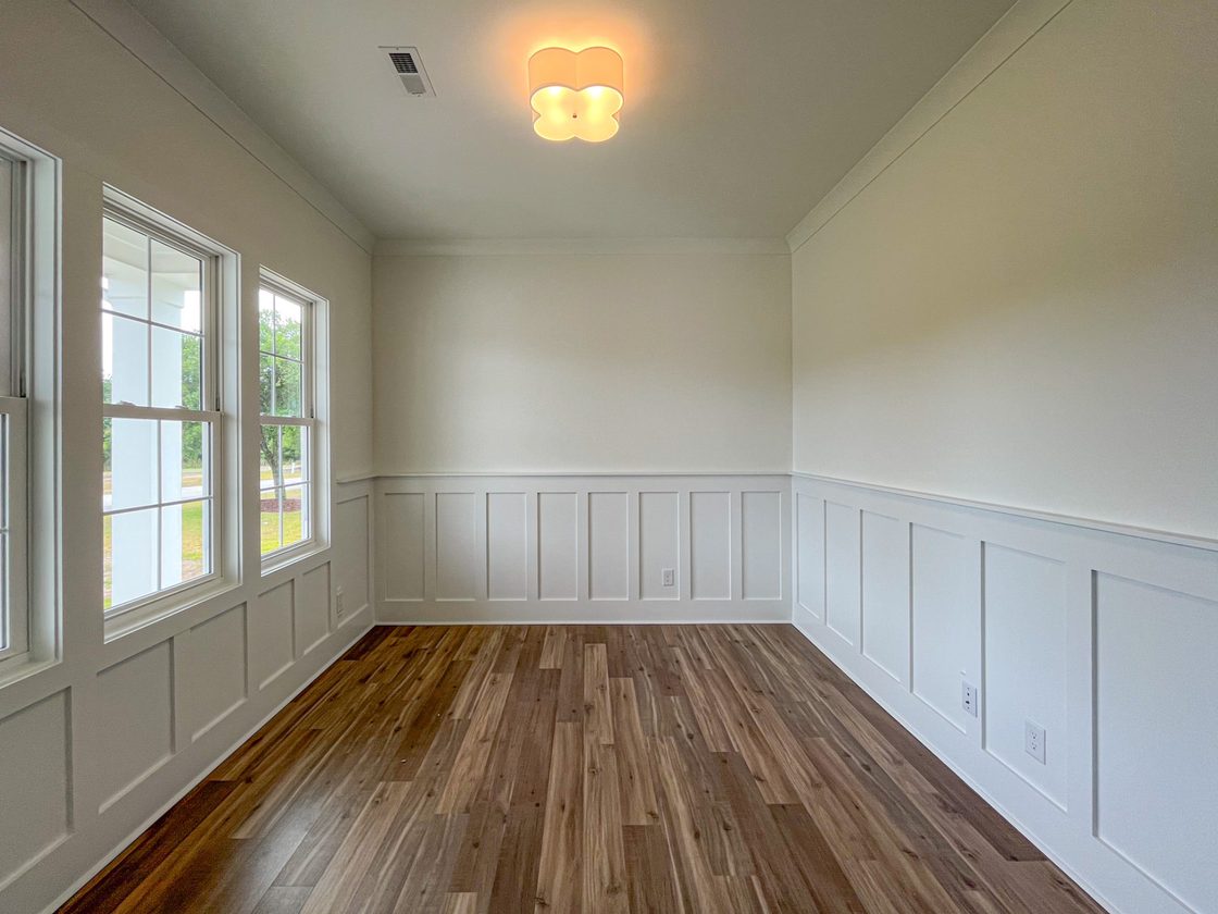 Room with wainscot panelling and wide plank flooring
